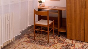 A room with a wooden desk, a chair, a radiator, a window with sheer curtains, a framed picture, and a wooden wardrobe. - Charming studio in  Roma with AC, WiFi, WASHING MACHINE for upto 3 person. (Roma)