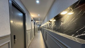 Un pasillo con puertas, iluminación empotrada y una pared de mármol.