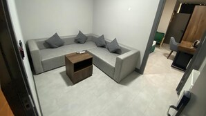 Una sala de estar moderna con un sofá seccional gris, una mesa de centro de madera y una mesita auxiliar.