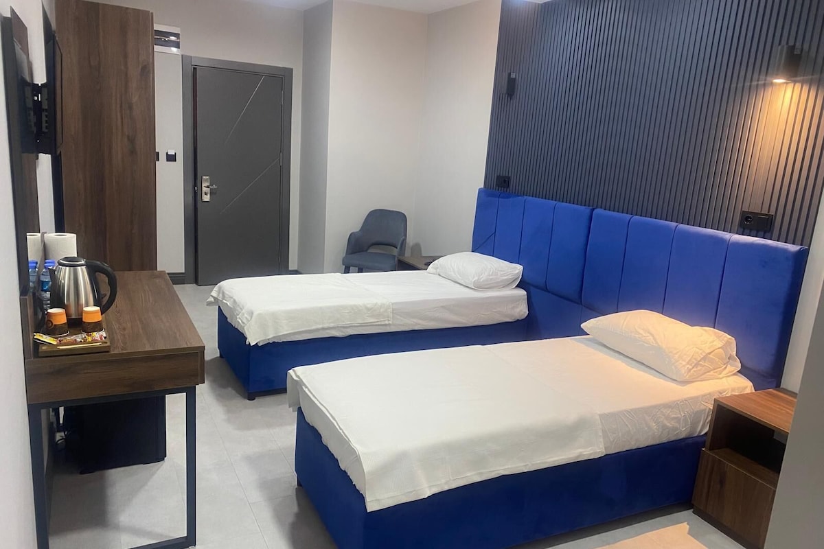 A hotel room with two beds, a desk with a coffee maker, and a chair.