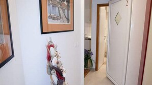 Ein Flur mit einem gerahmten Bild, einer dekorativen Vase und einer Tür mit einer Nummer.