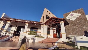 A hotel entrance with a stone facade, a triangular roof, and a sign reading "Altos de Amachuca Hotel Boutique." - Hotel Boutique Altos de Amaicha (Amaicha Del Valle)