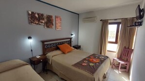 A bedroom with a bed, bedside tables, a chair, and artwork on the wall. - Hotel Boutique Altos de Amaicha (Amaicha Del Valle)