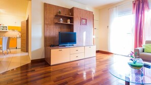 Ein modernes Wohnzimmer mit einer Holztrennwand, einem Flachbildfernseher und einem Glastisch mit einer dekorativen Schale.