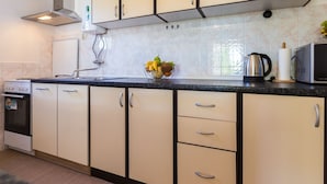 A modern kitchen with beige cabinets, a black countertop, a built-in oven, and a microwave. - Charming and Comfortable Rooms Zadar City - Classic Double Room (Zadar)