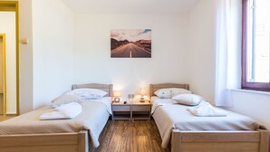 A double room with two single beds, a nightstand with a lamp, a painting of a road on the wall, and a window with curtains. - Charming and Comfortable Rooms Zadar City - Classic Double Room (Zadar)