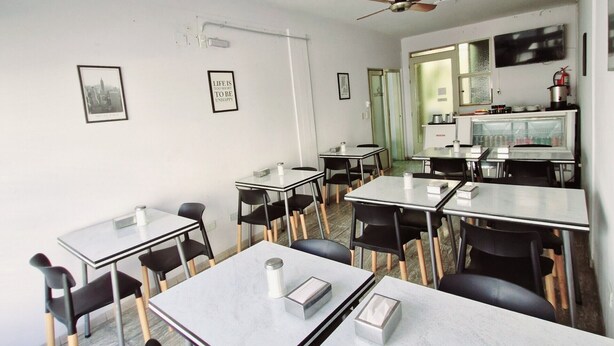 A classroom with tables and chairs, a ceiling fan, and a refrigerator with drinks. - HOTEL RESIDENCIAL CAMACHO (Cordoba)