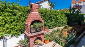 A brick-built outdoor oven with a chimney, surrounded by potted plants and a garden. - Charming and Comfortable Rooms Zadar City - Standard Double Room (Zadar)