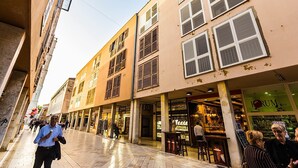 Eine Straße mit Gebäuden, Geschäften und Passanten.
