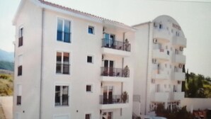 A multi-story hotel with balconies and a parking area.
