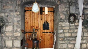 Un mur en pierre avec une porte en bois, un luminaire suspendu et une petite table avec une chaise.