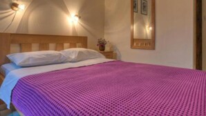 A bedroom with a wooden headboard, a pink textured bedspread, and two wall-mounted light fixtures. - Quaint & Affordable Stay in Budva Traditional Stone House - Standard Double Room 3 (Budva)