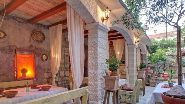An outdoor dining area with stone walls, wooden benches, and potted plants. - Quaint & Affordable Stay in Budva Traditional Stone House - Triple Room 5 (Budva)