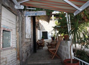 Un espace d’accueil avec un panneau indicateur, des chaises en bois et des plantes en pot.