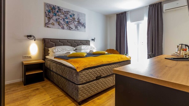 A modern bedroom with a large bed, a bedside table, a desk, and a wall-mounted artwork. - Charming and Elegant Rooms Zadar Historic Center - Classic Double room (Zadar)