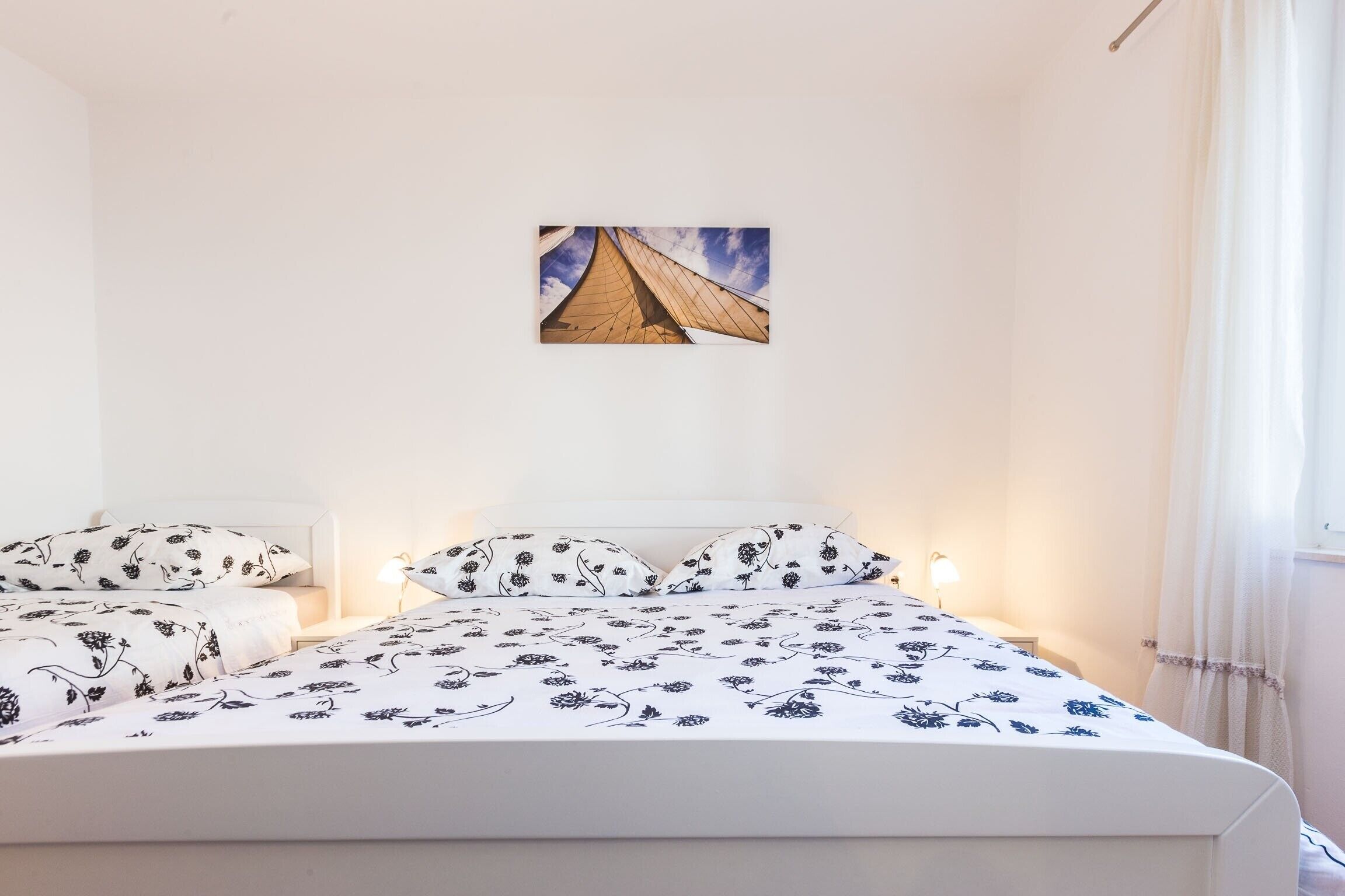 A bedroom with a bed, two bedside tables, and a wall-mounted picture.