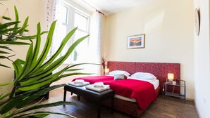 A hotel room with a bed, bedside table, and a large potted plant.