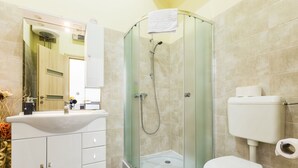 A bathroom with a glass-enclosed shower, a white sink, and a toilet.