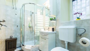 Un baño moderno con ducha de vidrio, lavamanos blanco y retrete.