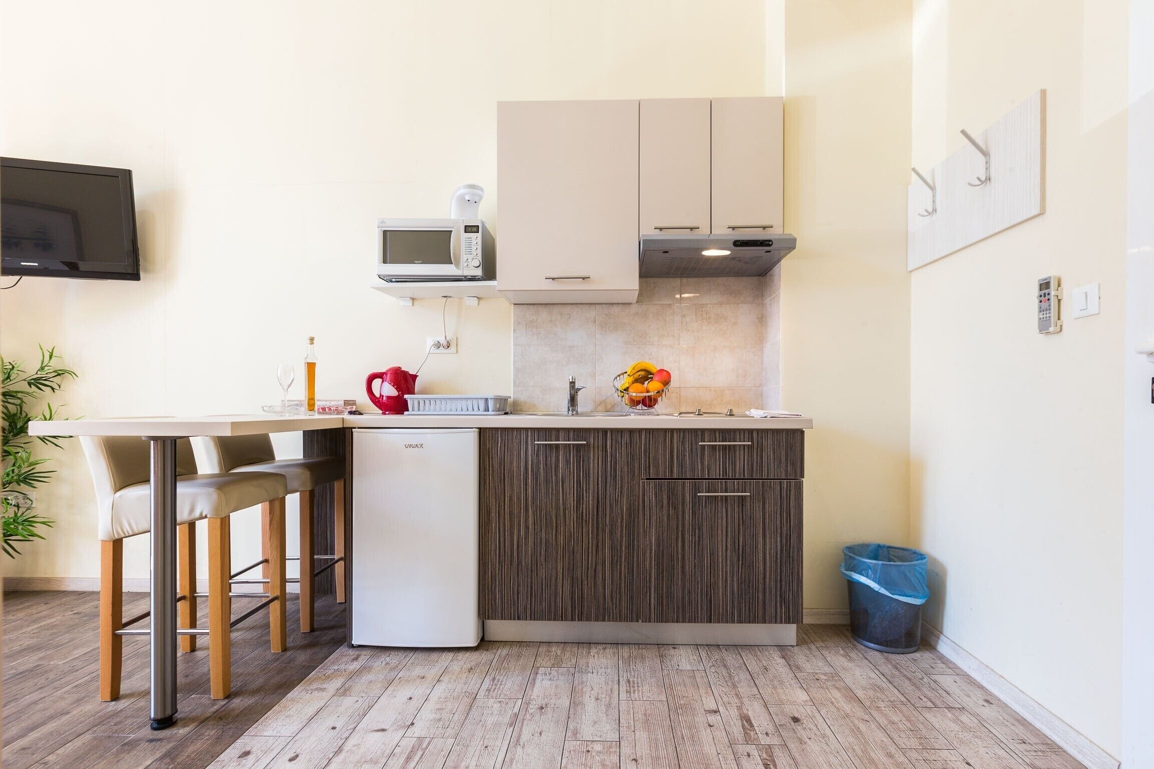 A compact kitchen with a central island, bar stools, a microwave, and a small refrigerator.