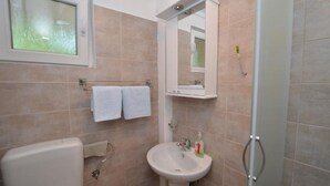 A bathroom with a toilet, sink, and shower. There is a towel rack with two white towels and a mirror above the sink. - Tivat Bliss Apartments - Studio with Balcony (Tivat)