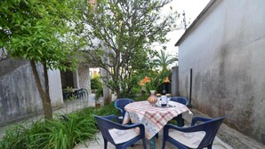 An outdoor patio with a table set for four, surrounded by blue chairs, a checkered tablecloth, and a vase with flowers. - Tivat Bliss Apartments - Studio with Balcony (Tivat)