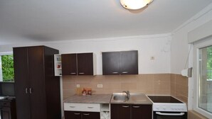 A compact kitchen with dark cabinets, a built-in oven, and a window. - Tivat Bliss Apartments - Studio with Balcony (Tivat)