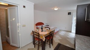 A small, clean room with a bed, a table with chairs, and a door leading to another room. - Tivat Bliss Apartments - Studio with Balcony (Tivat)
