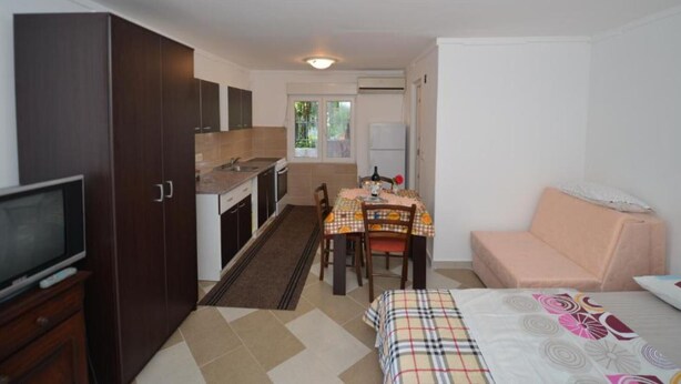 A compact room with a kitchenette, a dining area with a table and chairs, a bed, and a television. - Tivat Bliss Apartments - Studio with Balcony (Tivat)