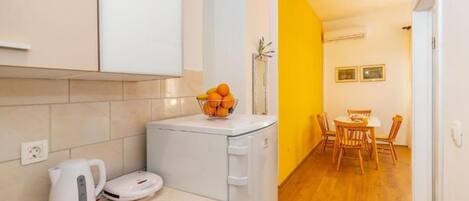 A compact kitchen with a kettle, a scale, and a fruit bowl on the counter.