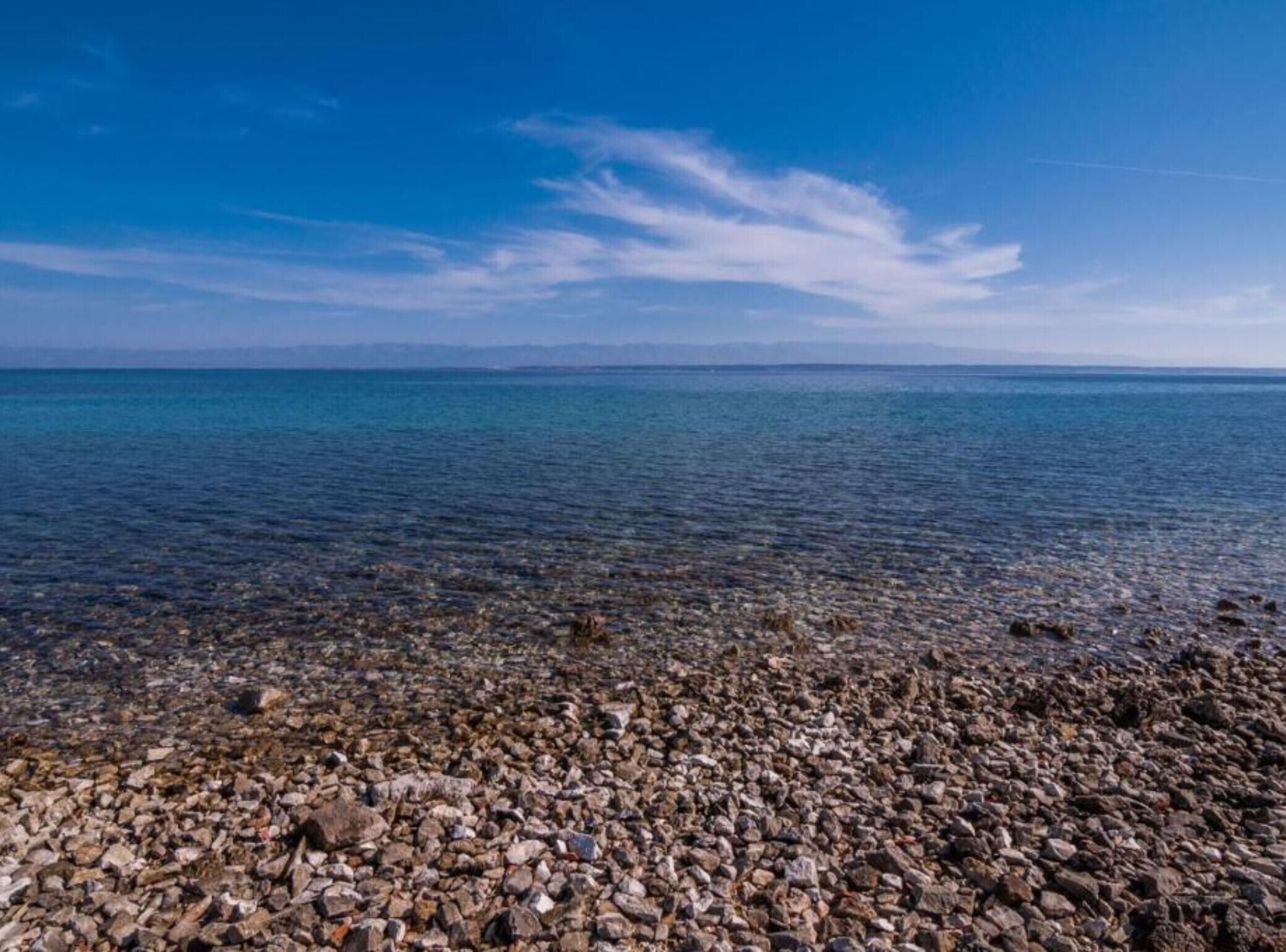 Una costa rocosa con agua cristalina y un horizonte lejano.