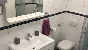 Un baño con lavamanos, espejo y retrete blancos.