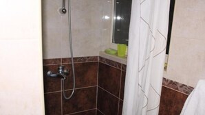 Un baño con ducha, espejo y barra para toallas.