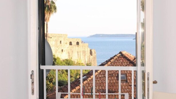 Un balcón con vistas a una pared de piedra histórica y una masa de agua.