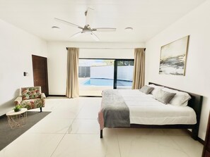 A modern bedroom with a large bed, a ceiling fan, a view of a swimming pool, and a door to the left. - Tamarindo Sunset Beach House, Costa Rica Pura Vida! (Tamarindo)