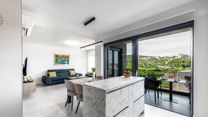 Ein moderner Wohnraum mit Kücheninsel, Essbereich und Balkon mit Blick auf die Stadt.
