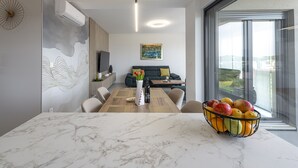 Ein modernes Wohnzimmer mit Essbereich, großem Fenster und Blick auf die Stadt.