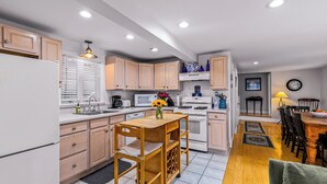 A modern kitchen with wooden cabinets, a dining area with a table and chairs, and a small seating area with a sofa.
