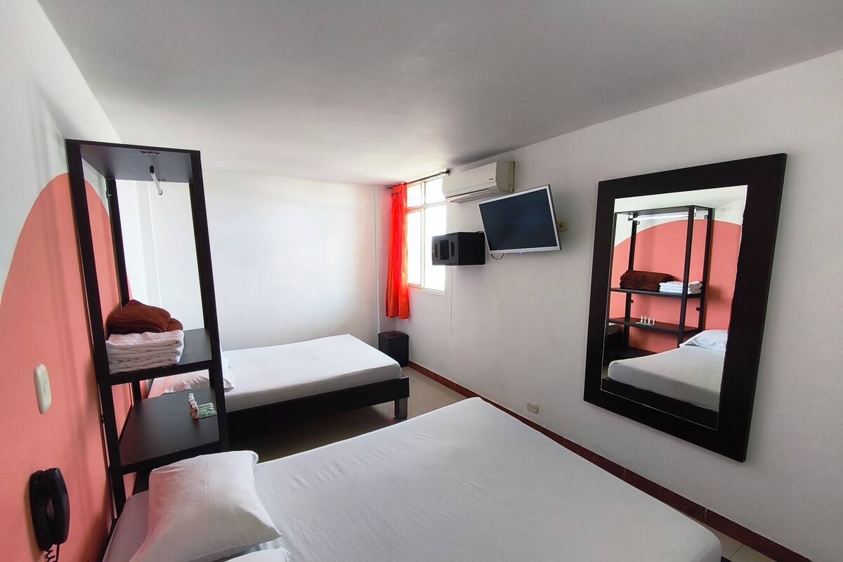 Een hotelkamer met twee bedden, een televisie, een spiegel, een telefoon en een airconditioner.