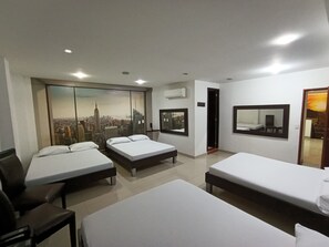 A hotel room with three beds, a large window with a cityscape view, a mirror, and an air conditioning unit. - Hotel Cielo de Tambores (Cali)