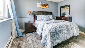 A bedroom with a bed, a nightstand, a lamp, a dresser, a mirror, and a window with curtains. - 11 Mi to Kincaid Park: Convenient + Cozy Apt! (Anchorage)