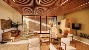 Una sala de estar moderna con techo de listones de madera, sofá de cuero y varias opciones de asientos.