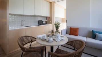 A modern kitchen with white cabinets, a microwave, and a dining area with wicker chairs and a round table.