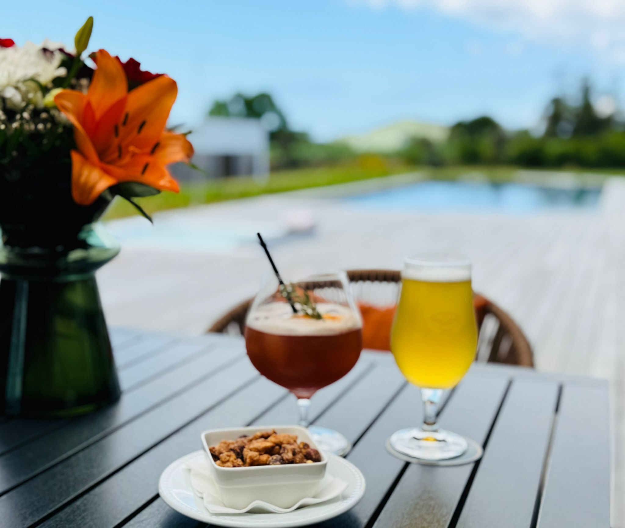 A dining table with a bowl of food, a glass of beer, and a glass of wine.