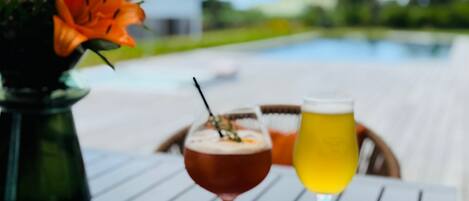 A dining table with a bowl of food, a glass of beer, and a glass of wine.