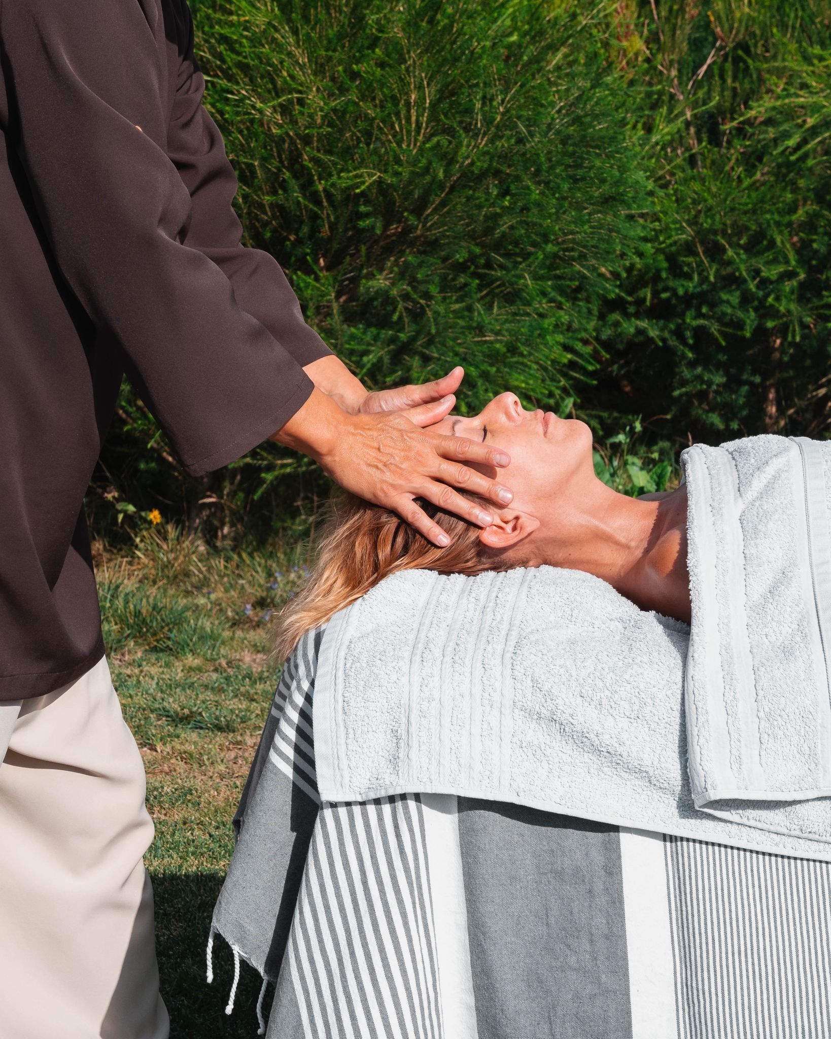 A person receiving a head massage outdoors.