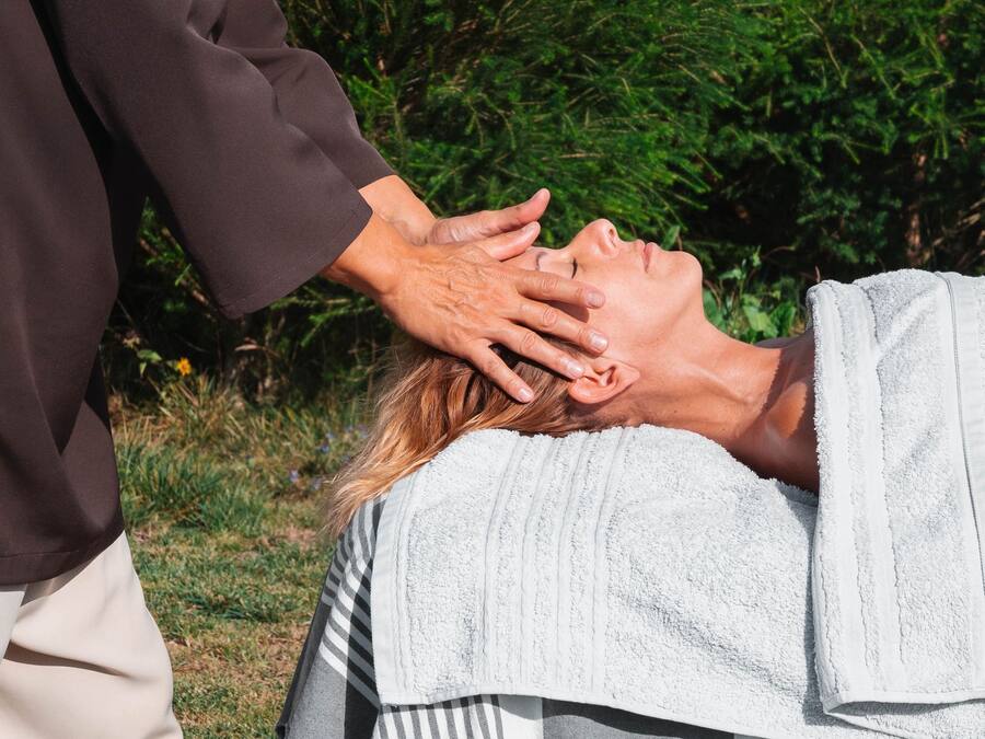 A person receiving a head massage outdoors.