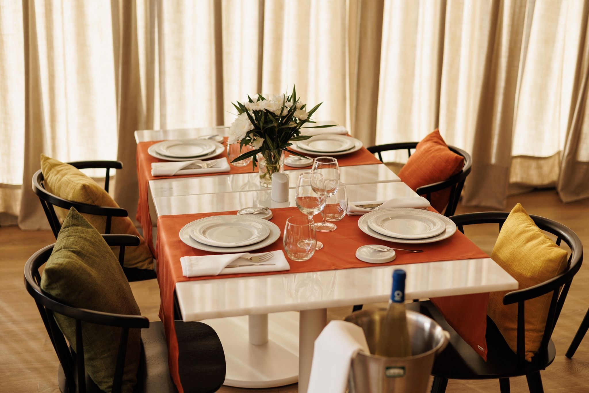 Una mesa de comedor dispuesta con platos, vasos y un jarrón de flores.
