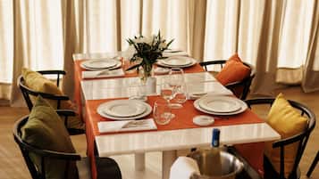 Una mesa de comedor dispuesta con platos, vasos y un jarrón de flores.