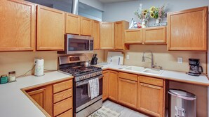 A kitchen with wooden cabinets, a stainless steel stove, a microwave, a sink, and a coffee maker. - 6 Mi to Lake Meridian Park: Auburn Home w/ Yard (Auburn)